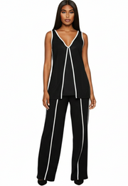 Woman wearing a black sleeveless top and pants with white piping on a white background