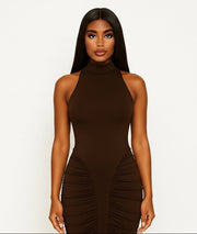 Woman wearing a brown halter neck dress with ruched sides on a white background