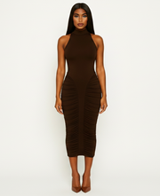 Woman wearing a brown halter neck dress with ruched sides on a white background