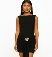 Woman wearing a black dress with a decorative brooch on a white background