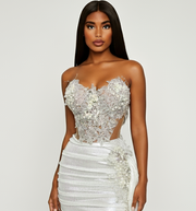 Woman wearing a white and silver beaded dress on a plain background