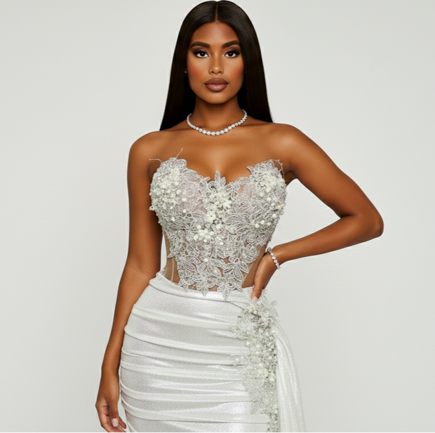 Woman wearing a strapless silver and white evening gown on a plain background