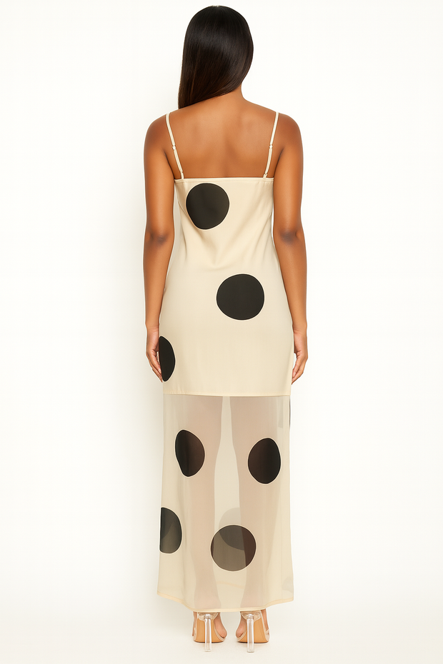Woman wearing a beige slip dress with black polka dots on a white background