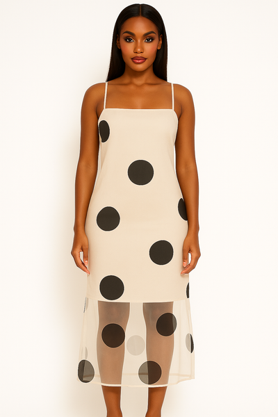 Woman wearing a cream slip dress with black polka dots on a white background
