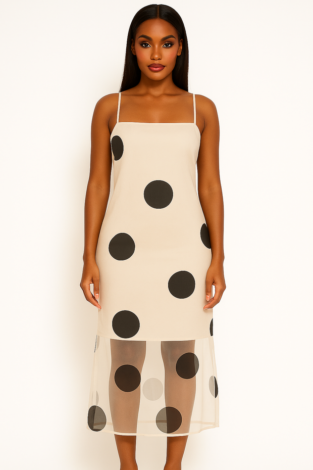 Woman wearing a cream slip dress with black polka dots on a white background