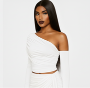 Woman wearing a white one-shoulder dress against a plain background
